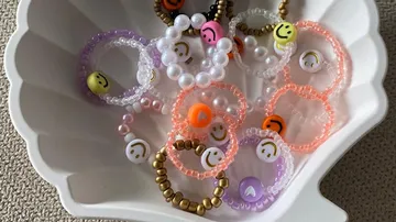Bunte Perlenarmbänder in einer Muschelschale.