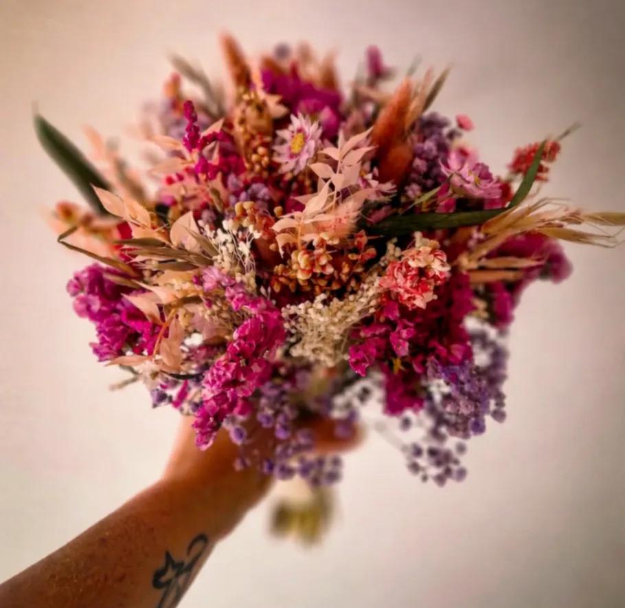 Bunter Trockenblumenstrauß in der Hand gehalten.