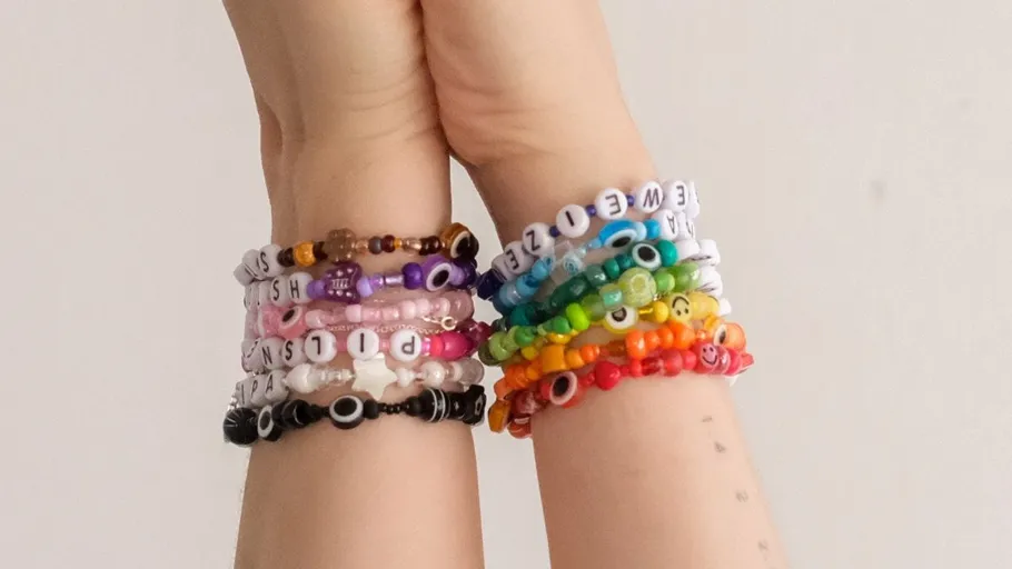 Hands wearing colorful beaded bracelets together.