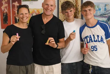 Smiling family holding chalk sticks indoors.