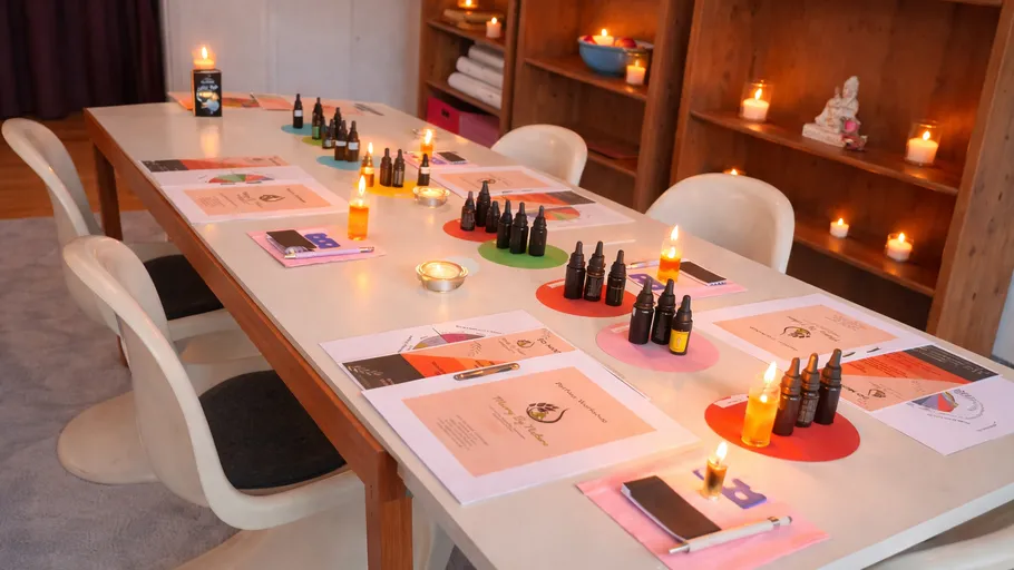 Tisch mit ätherischen Ölen, Kerzen und Papieren gedeckt.