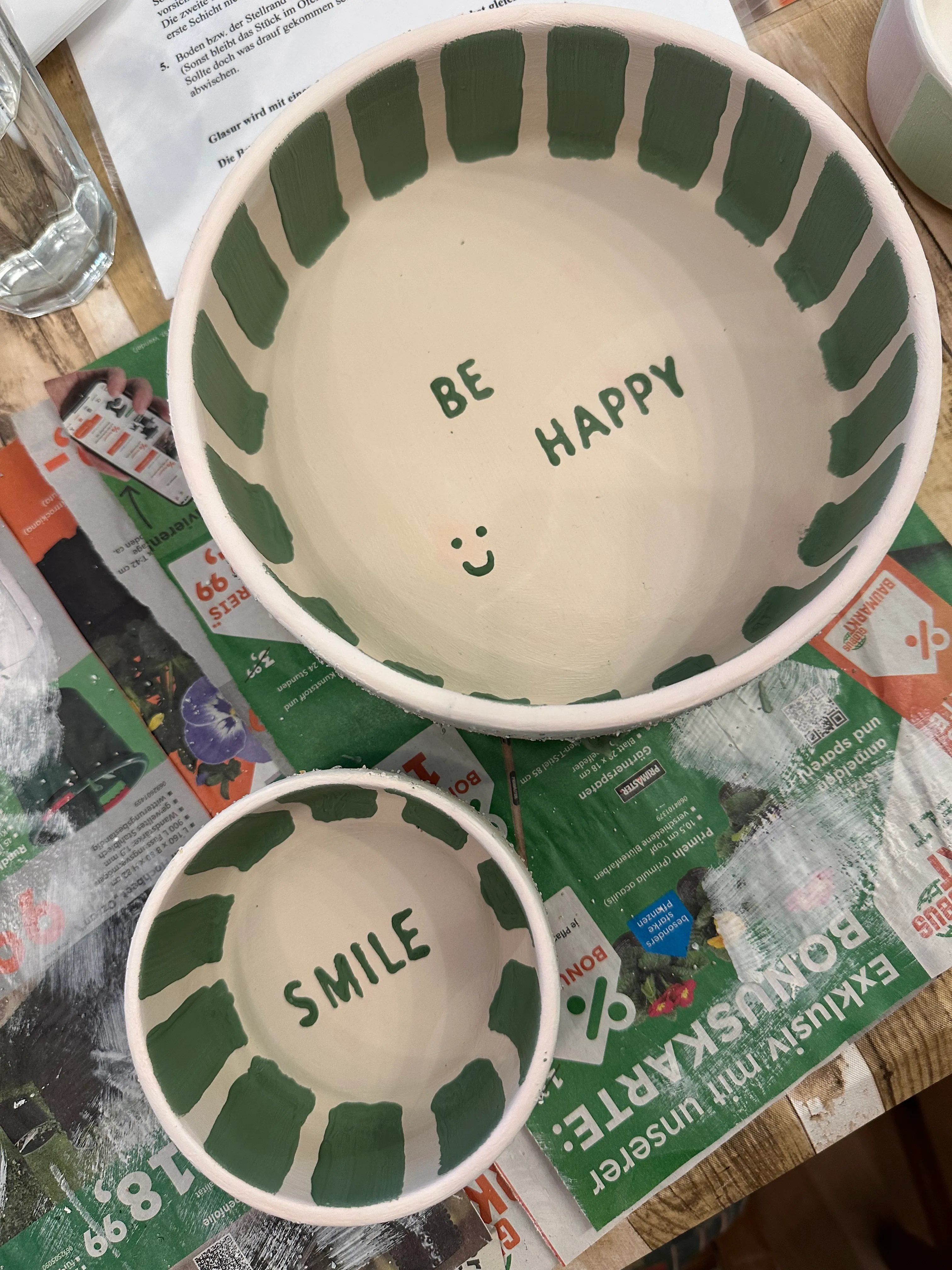Two bowls with green lettering on newspaper.