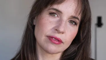 Woman with brown hair, neutral expression, indoors.