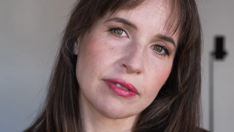 Woman with brown hair, neutral expression, indoors.