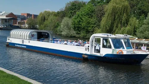 Sightseeing boat cruising along a lush riverside.