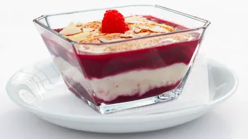 Layered dessert with raspberry and almond garnish.