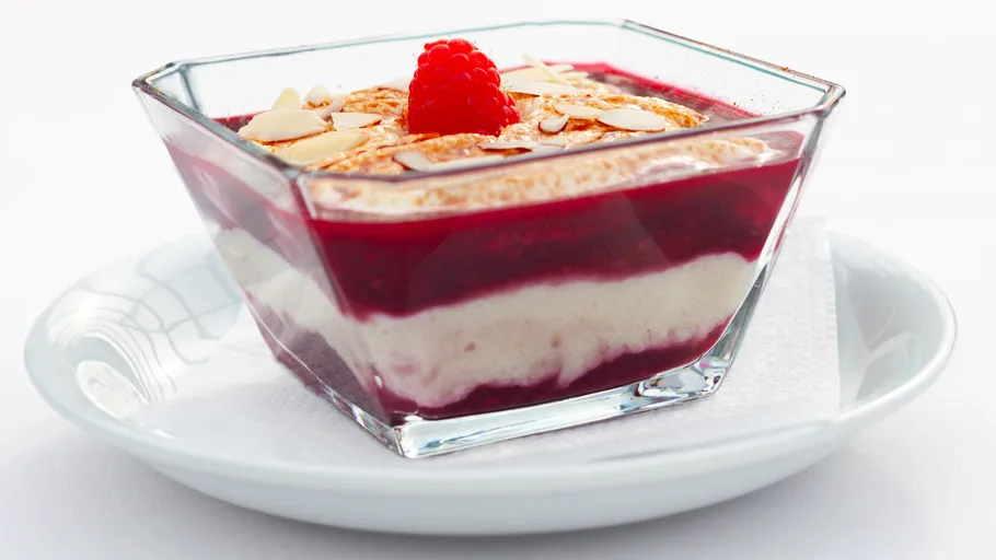 Layered dessert with raspberry and almond garnish.