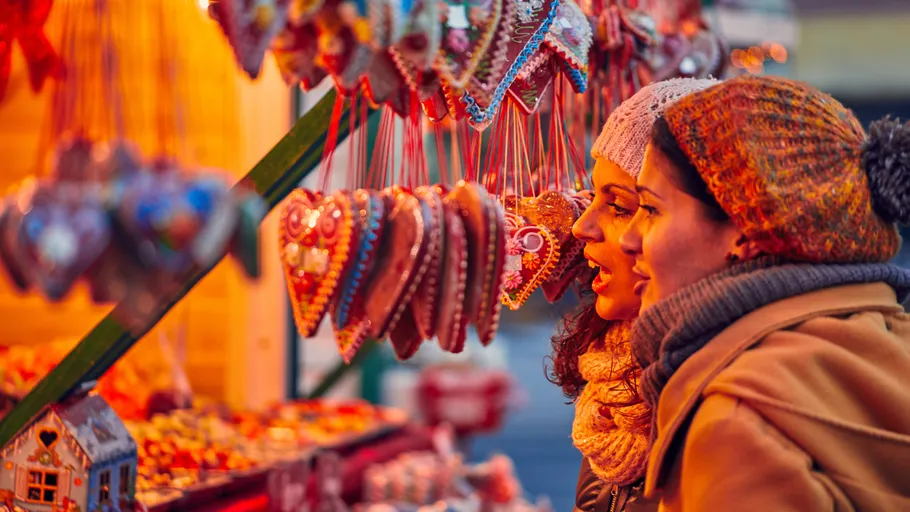 Two women admire gingerbread hearts at a market.