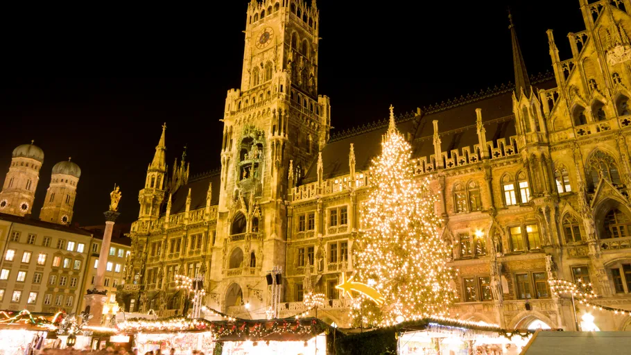 Festlicher Weihnachtsmarkt vor beleuchtetem Gebäude.