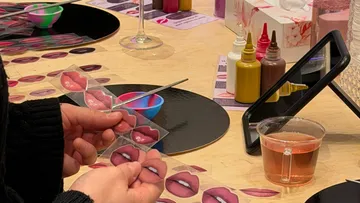 Person holding lip color samples at makeup table.