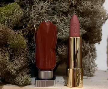 Lippenstift und Glosstuben in moosiger Umgebung.