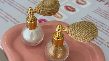 Zwei Glitzerflaschen auf rosa Tablett.