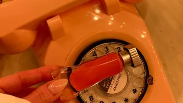 Hand holding sauce sample above vintage phone.