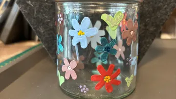 Glasgefäß mit bunten gemalten Blumen.