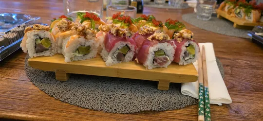 Sushirollen auf Holztablett mit Essstäbchen.