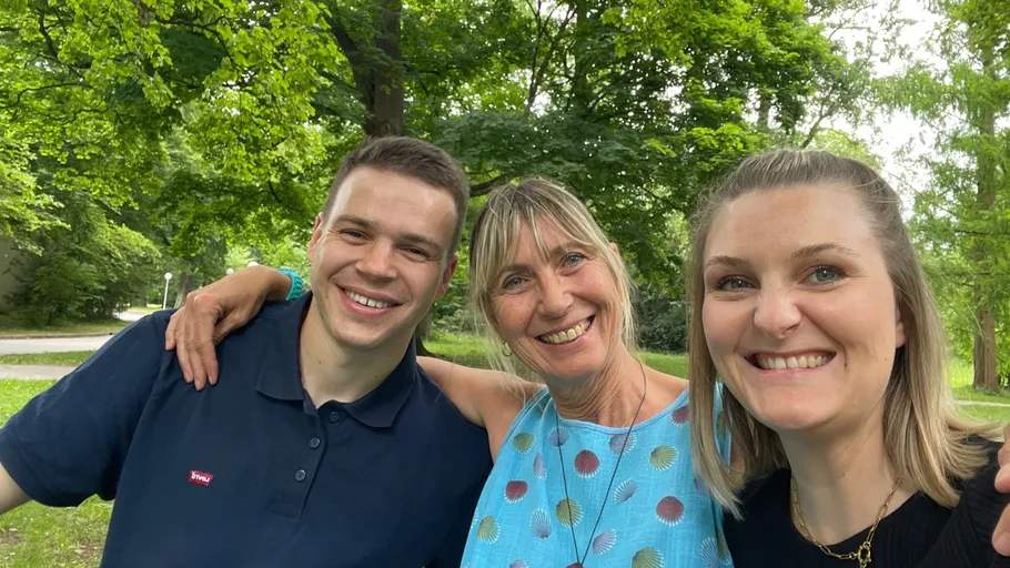 Three people smiling in a green park.