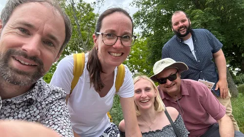 Group of five people smiling outdoors.