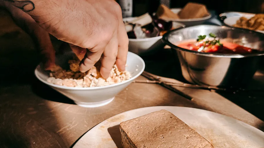 Hands mixing food in a bowl, kitchen table.