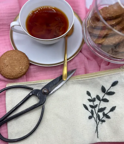 Tea cup with cookies and scissors on fabric.