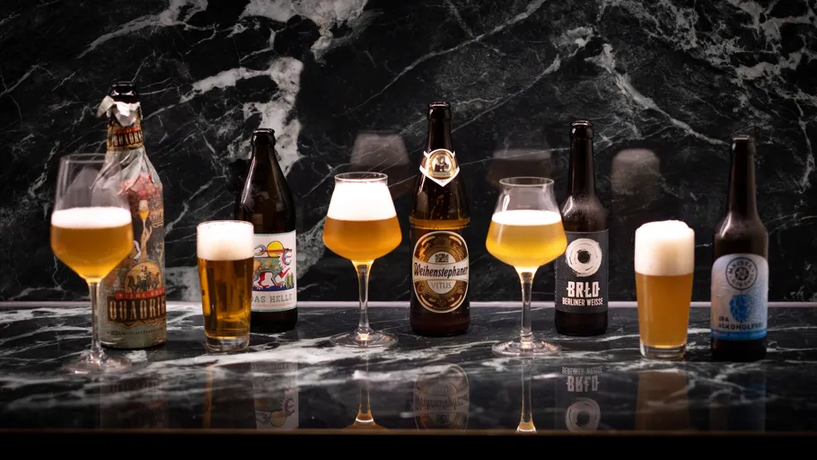 Verschiedene Bierflaschen und Gläser auf Marmortisch.