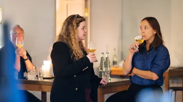 Drei Personen trinken Bier in entspannter Umgebung.