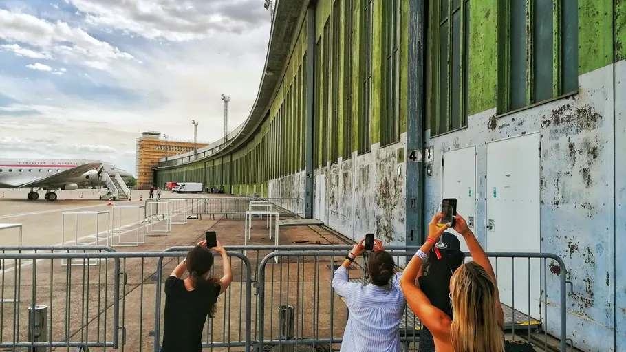 People take photos of vintage plane outside hangar.