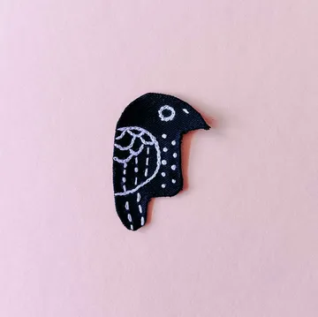 Black bird embroidery on pink background.