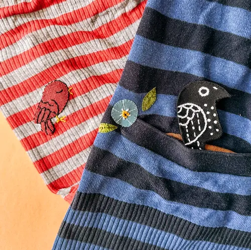 Gestreifte Stoffe mit gestickten Vögeln und Blume.