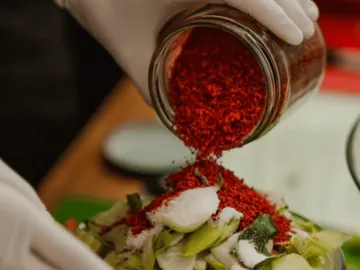 Spice is poured over fresh lettuce in kitchen environments.