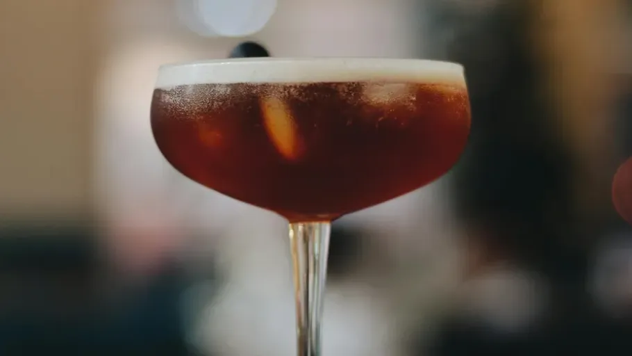 Cocktailglas mit dunklem Getränk und Schaum.