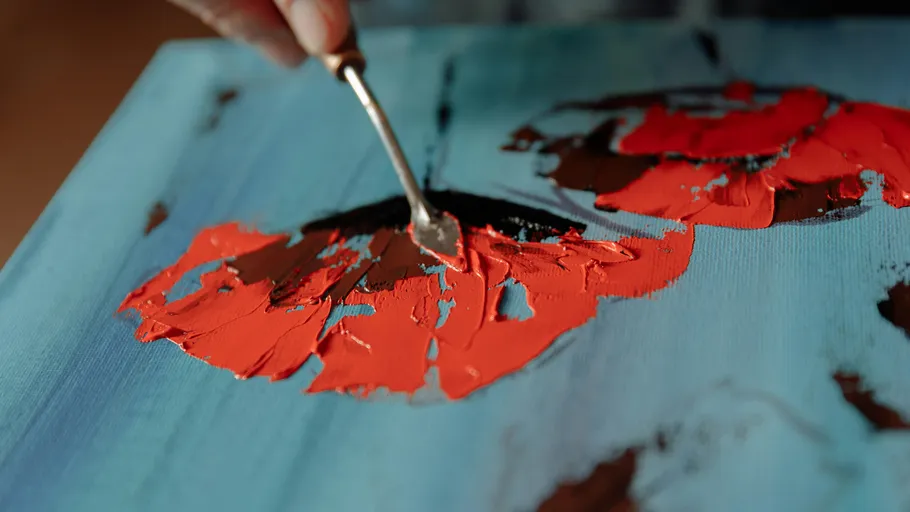 Malmesser trägt rote Farbe auf Leinwand auf.