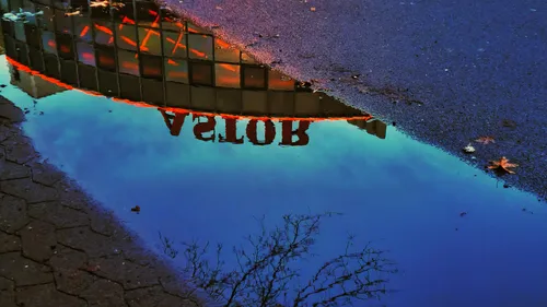 Building sign reflection in water puddle.
