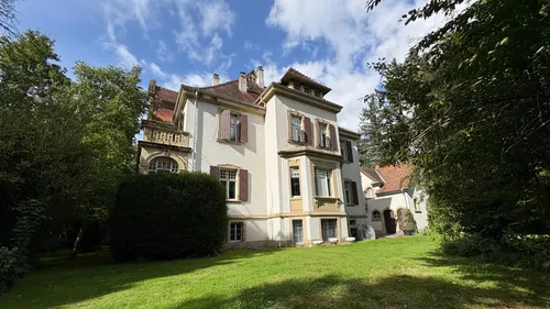 Großes Haus mit Garten, umgeben von Bäumen.