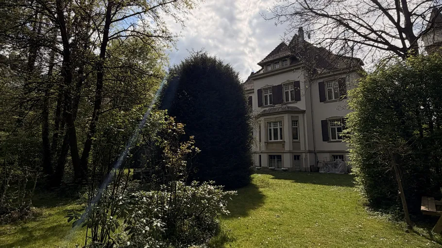 Large house with garden surrounded by trees.