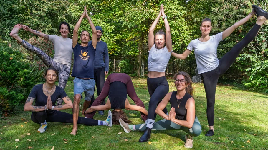 People in various yoga poses outdoors.