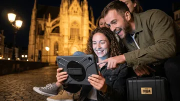 Group using tablet in city square at night.