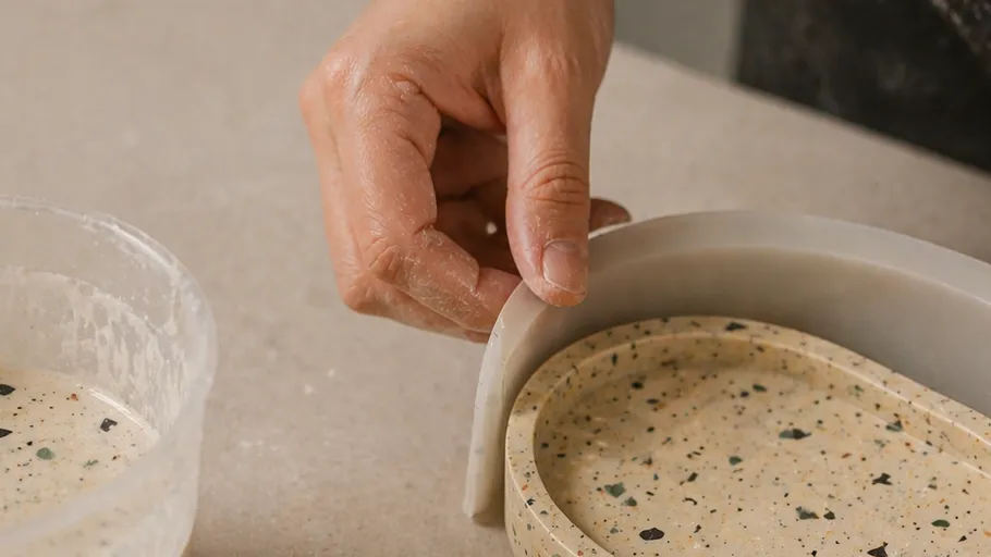 Hand removing mold from terrazzo tray.