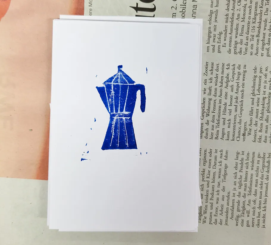 Blauer Kaffeekannenstempel auf weißem Papier.