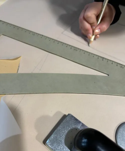 Hand drawing with pencil using a large ruler.