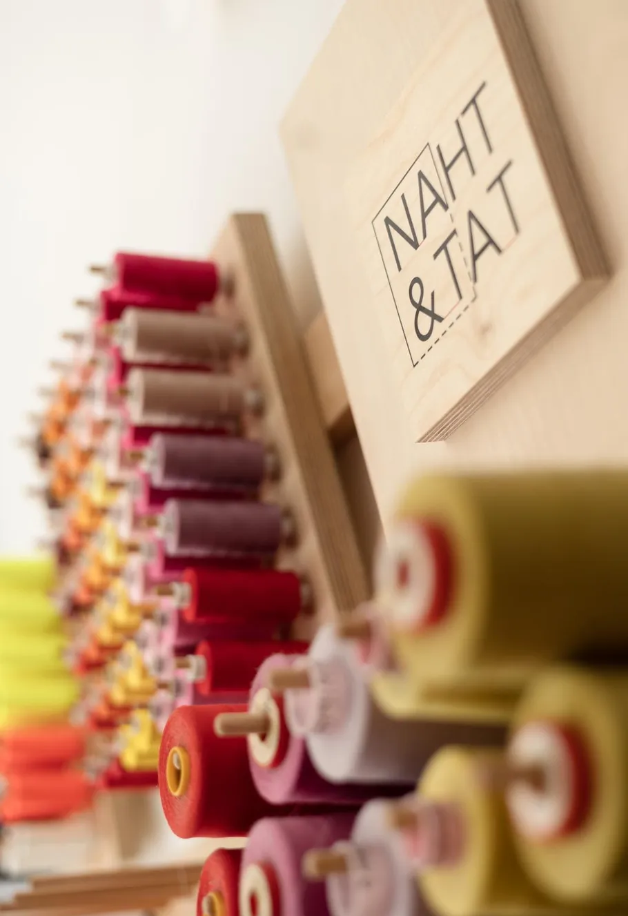 Colorful thread spools on wooden holders, sewing studio.