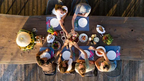 People toasting at a wooden outdoor table.
