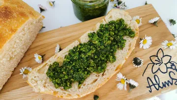 Bread with green spread on wooden board.