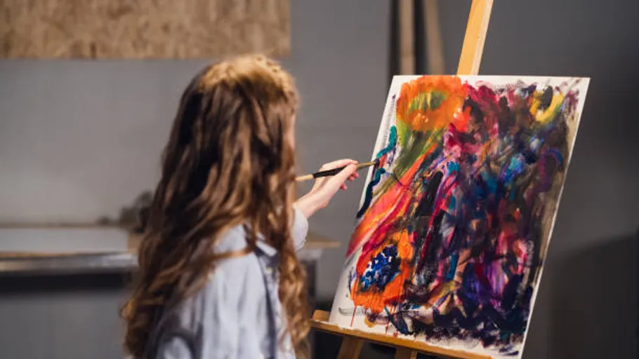 Person painting abstract art on canvas indoors.