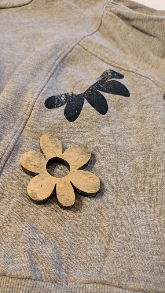 Wooden flower on gray fabric with print.