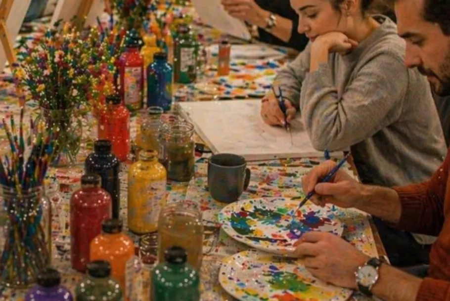 People painting at colorful art studio.