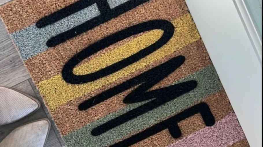 Colorful doormat with 'HOME' text by shoes.