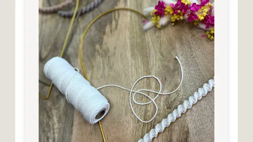 White thread and flowers on wooden table.