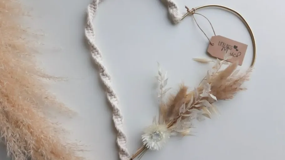 Herzförmige Dekoration mit Trockenblumen auf Tisch.