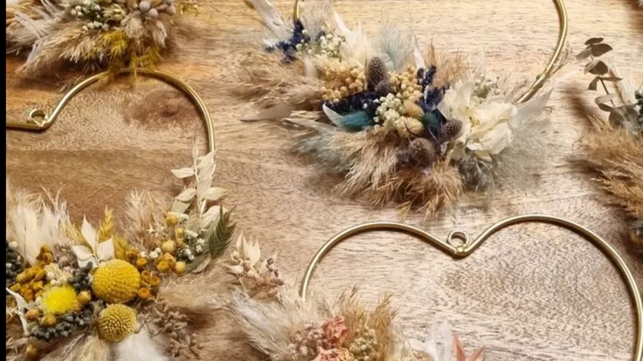 Dekorative herzförmige Kränze mit Trockenblumen auf Holz.