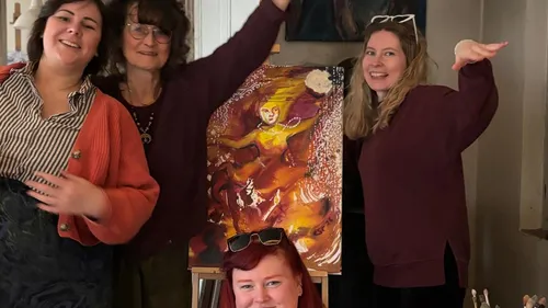 Vier Personen posieren mit abstraktem Gemälde drinnen.